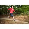 Young woman running outdoors in a forest, going fast (motion blurred image)