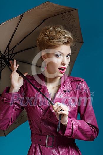 Young woman with umbrella on blue
