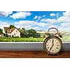 View of house on summer vineyard landscape from window with alarm clock