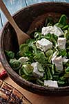 Salad of fresh greens and feta cheese in a wooden bowl