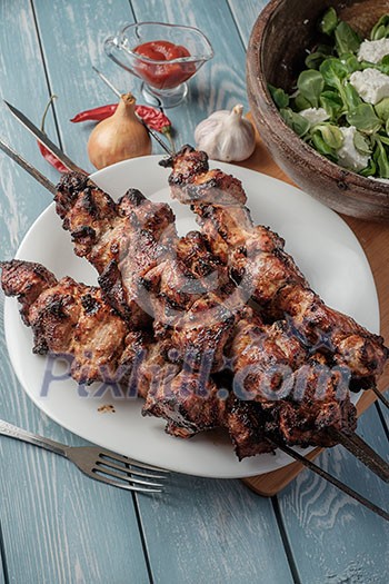 Shashlik with salad on the wooden table