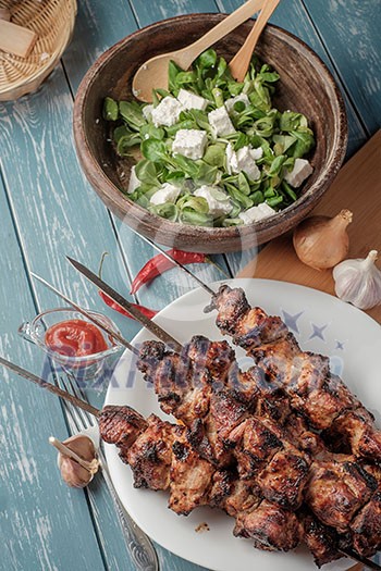 Shashlik with salad on the wooden table Shashlik with salad on the wooden table