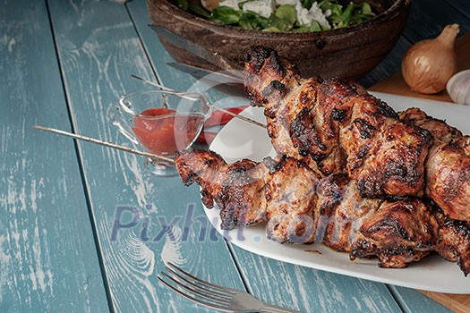 Shashlik with salad on the wooden table