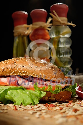 Sandwich on a wooden table with slices of bacon, lettuce and tomatoes. Sandwich on a wooden table with slices of bacon, lettuce and tomatoes.
