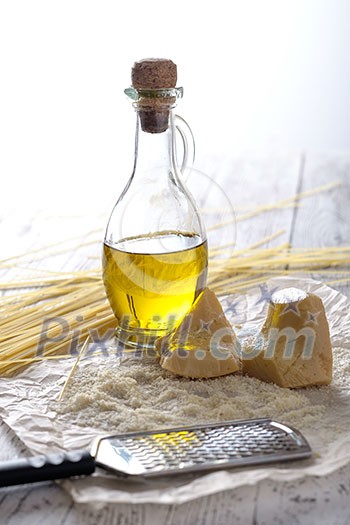 Grated parmesan cheese, bottle of olive oil and metal grater on wooden table. Grated parmesan cheese, bottle of olive oil and metal grater on wooden table.