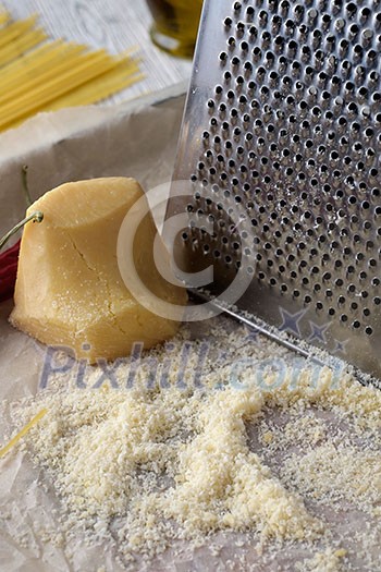 Close-up grated parmesan cheese and metal grater on wooden table. Close-up grated parmesan cheese and metal grater on wooden table.