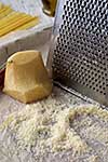 Close-up grated parmesan cheese and metal grater on wooden table.