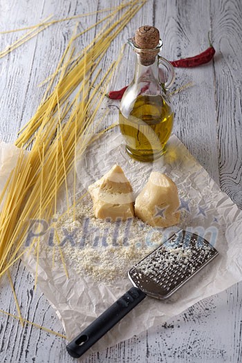 Grated parmesan cheese, bottle of olive oil and metal grater on wooden table. Grated parmesan cheese, bottle of olive oil and metal grater on wooden table.