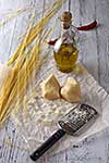Grated parmesan cheese, bottle of olive oil and metal grater on wooden table.