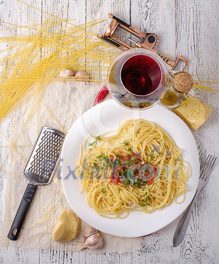 Italian pasta cooked in a rustic style with a sauce of fresh tomatoes and garlic on a wooden table with a glass of red wine. Italian pasta cooked in a rustic style with a sauce of fresh tomatoes and garlic on a wooden table with a glass of red wine.