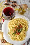 Italian pasta cooked in a rustic style with a sauce of fresh tomatoes and garlic on a wooden table with a glass of red wine. Top view.