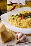 Italian pasta cooked in a rustic style with a sauce of fresh tomatoes and garlic on a wooden table with a glass of red wine. Close-up.