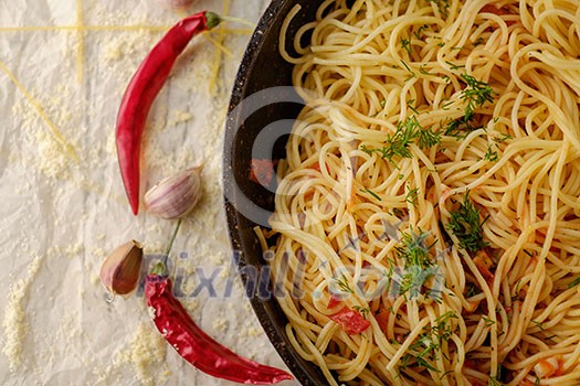 Spaghetti Pasta in airon frying pan with garlic, tomatoes and spices.