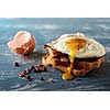 Breakfast - sandwich with fried egg and bacon over blue wooden table