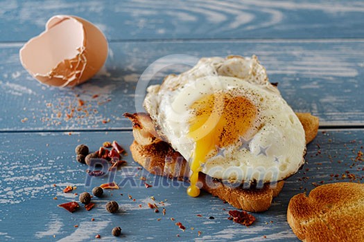 Breakfast - sandwich with fried egg and bacon over blue wooden table Breakfast - sandwich with fried egg and bacon over blue wooden table