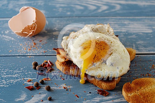 Breakfast - sandwich with fried egg and bacon over blue wooden table