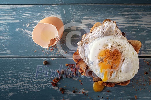 Breakfast - sandwich with fried egg and bacon over blue wooden table Breakfast - sandwich with fried egg and bacon over blue wooden table