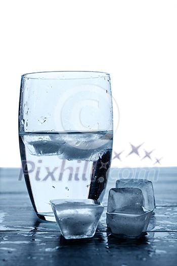 Glass of water and melting ice cubes on a wooden table Glass of water and melting ice cubes on a wooden table