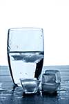 Glass of water and melting ice cubes on a wooden table