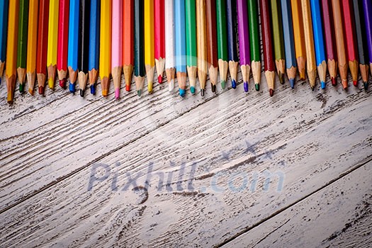 Colored pencils in a row on wooden background Colored pencils in a row on wooden background