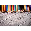 Colored pencils in a row on wooden background