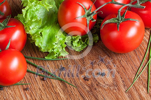 red tomatoes with green salad on wood