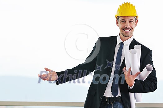 happy young architect portrait with helmet and blueprints indoor at new big bright appartment and construction site