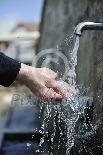 clear fresh mountain water falling on hands outdoor in nature