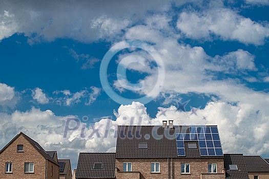 New houses with solar panels on roof under blue sky and clouds