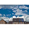 New houses with solar panels on roof under blue sky and clouds