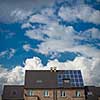 New houses with solar panels on roof under blue sky and clouds