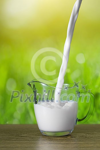 Milk pouring into the glass on nature background Milk pouring into the glass on nature background
