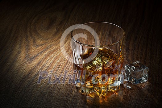 Whiskey with ice in glass on the wood Whiskey with ice in glass on the wood