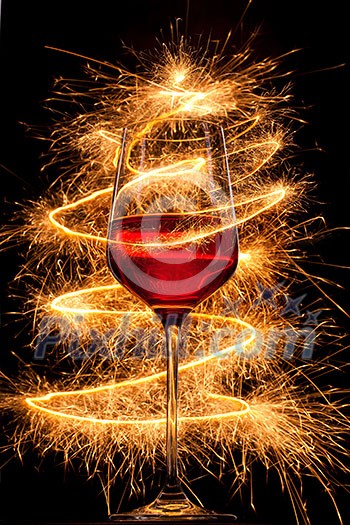 Wine in glass with burning sparklers on black background