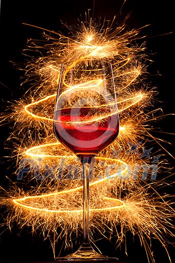 Wine in glass with burning sparklers on black background Wine in glass with burning sparklers on black background