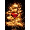 Wine in glass with burning sparklers on black background