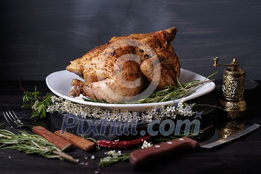 Roasted chicken with spices and herbs on a wooden table. Tasty food. Rustic style.