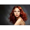 Portrait of a young ginger woman on a dark background. Low key. Long Curly Red Hair. 