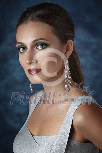 Beautiful elegant woman with evening make-up and long earrings. Looking into the camera.
