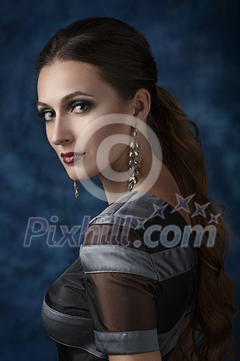 Beautiful elegant woman with evening make-up and long earrings. Looking into the camera over his shoulder, half-turned.