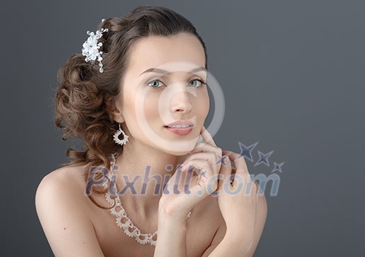 Beauty Portrait. Beautiful Woman Touching her Face. Perfect Fresh Skin. Isolated on Grey Background. Pure Beauty Model. Youth and Skin Care Concept. Wedding make-up.