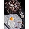 Quail eggs in the nest and a fried egg on a wooden board