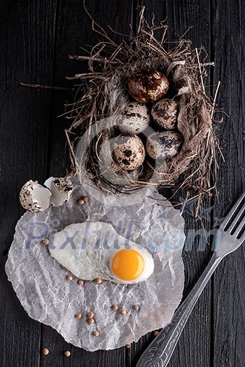 Quail eggs in the nest and a fried egg on a wooden board Quail eggs in the nest and a fried egg on a wooden board