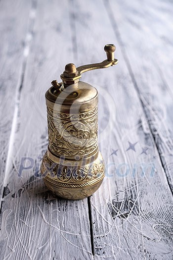 Vintage still life with brass pepper mill standing on the wooden background Vintage still life with brass pepper mill standing on the wooden background