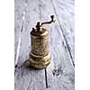 Vintage still life with brass pepper mill standing on the wooden background