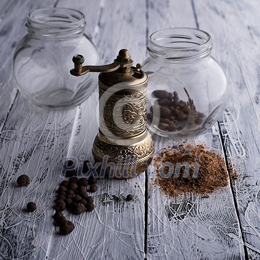 Vintage still life with brass pepper mill standing on the wooden background Vintage still life with brass pepper mill standing on the wooden background