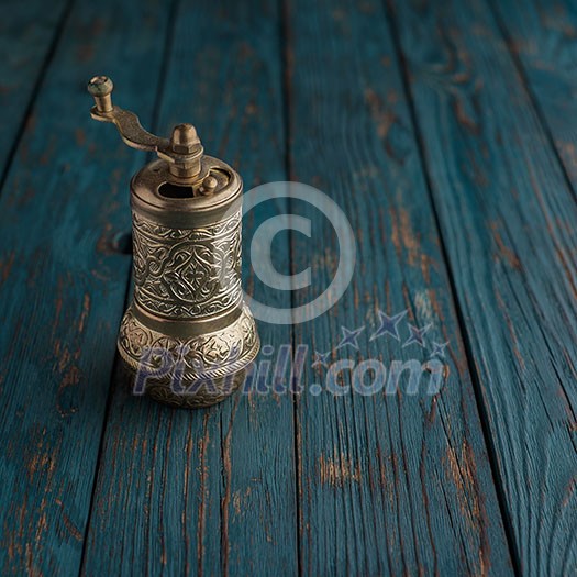 Vintage still life with brass pepper mill standing on the wooden background Vintage still life with brass pepper mill standing on the wooden background