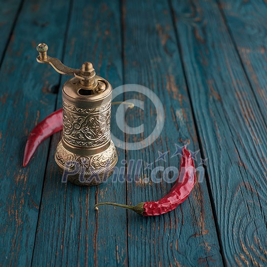 Mill for pepper and chili peppers on a wooden table Mill for pepper and chili peppers on a wooden table