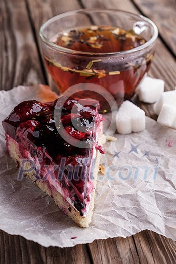 A piece of berry pie and a cup of tea on a wooden background. A piece of berry pie and a cup of tea on a wooden background.