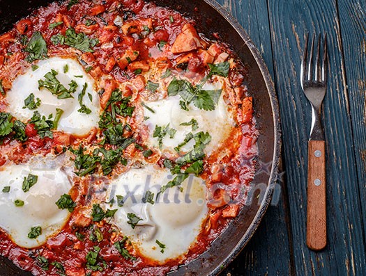 Fried eggs in a frying pan with tomatoes, sausage and greens. Fried eggs in a frying pan with tomatoes, sausage and greens.